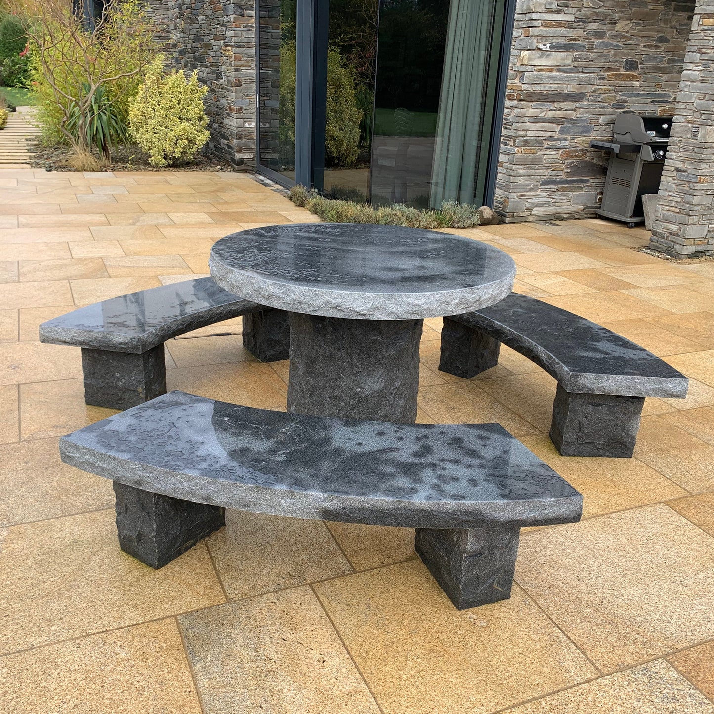 Black Granite picnic table and benches on a gold granite patio with a stone building in the background