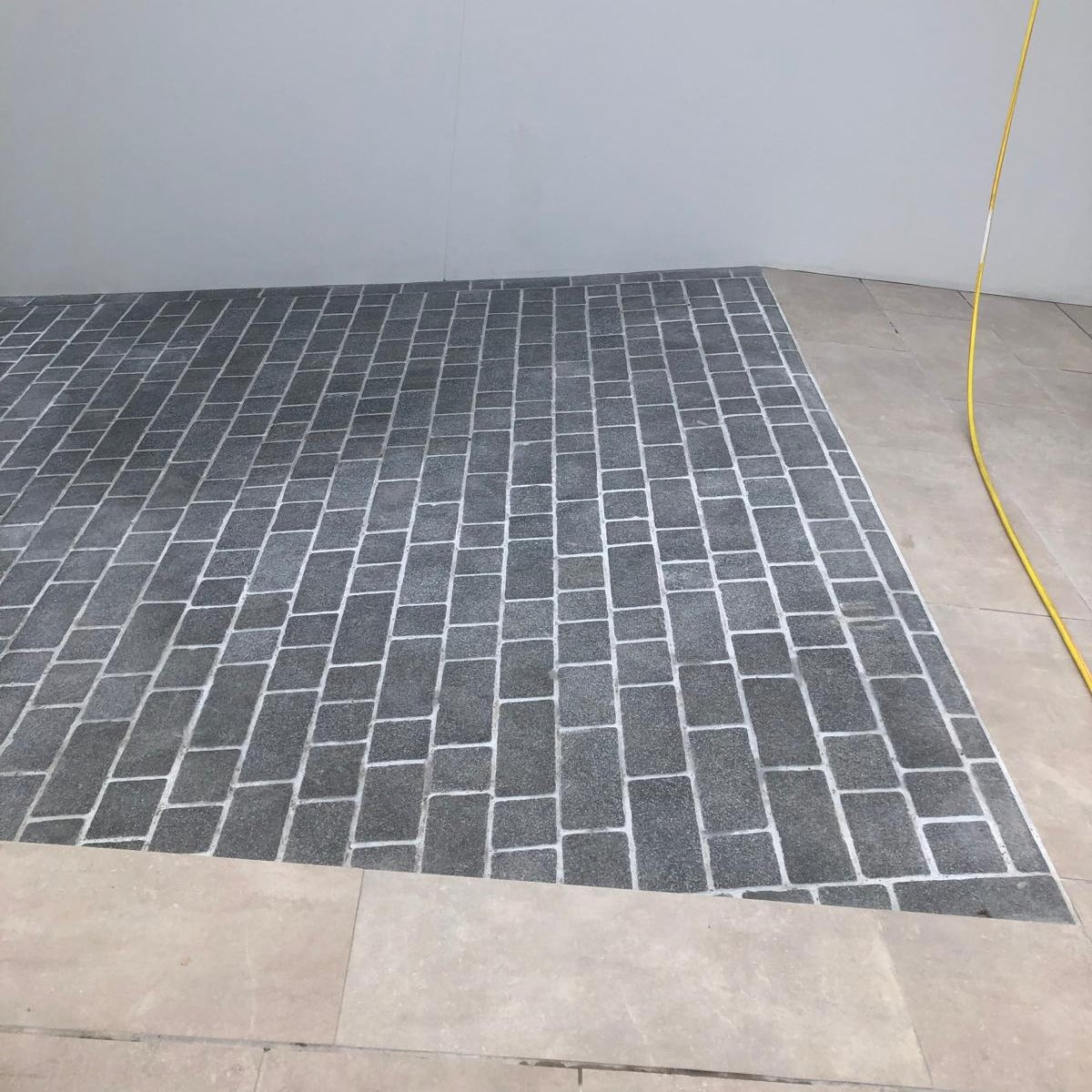 A pathway photographed dry laid out with Coachman's Black Granite Paving Setts, showing a contemporary look with a flamed surface finish and tumbled edges.