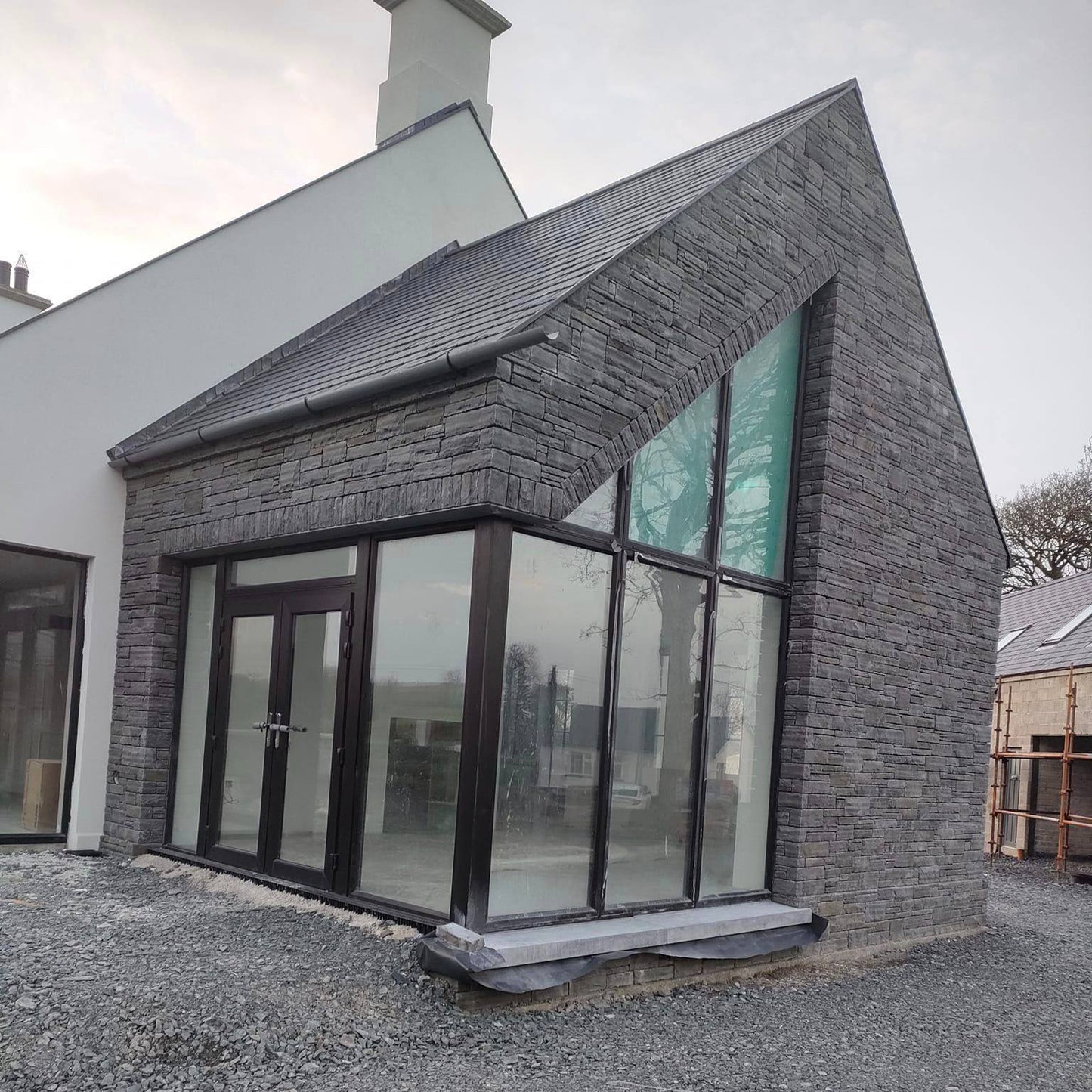 Modern new build with large windows. Walls are cladded in Liscannor Slate Stoneer Cladding.