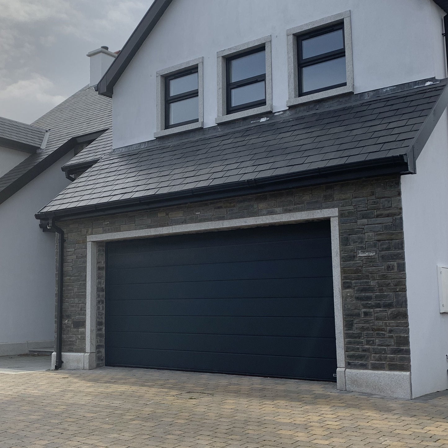 Modern house with a garage featuring bespoke door surround in Silver Granite.