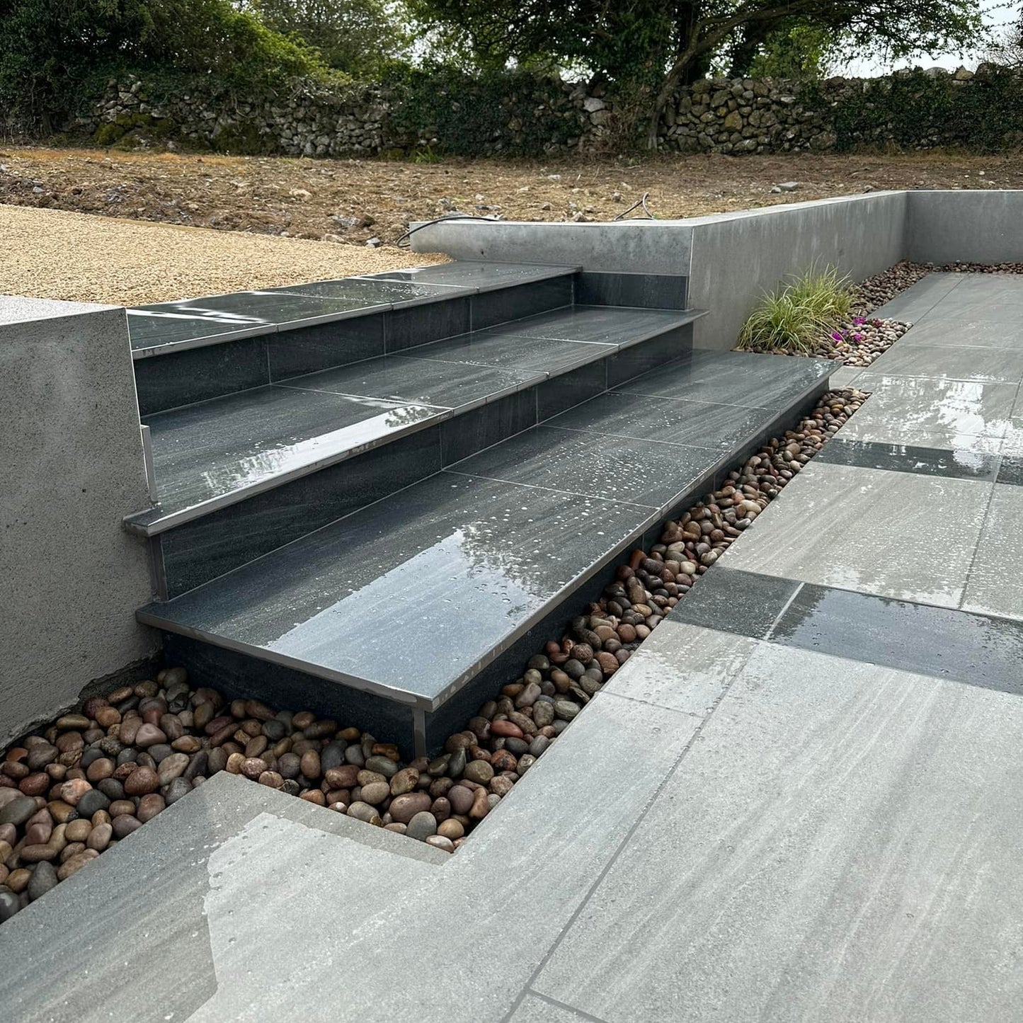 Patio steps leading up to raised garden completed using Smokey Jewel Range Porcelain Paving.