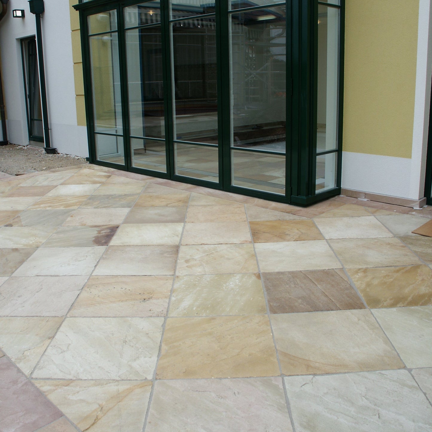 Paved area with a glass structure in the background. Paving is Tinted Mint Sandstone in 600 x 600mm size.