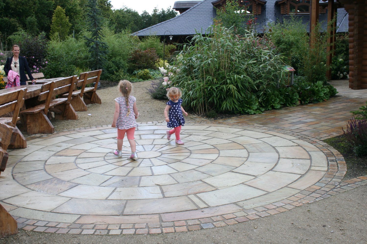 Two children playing on a natural sandstone paving circle.