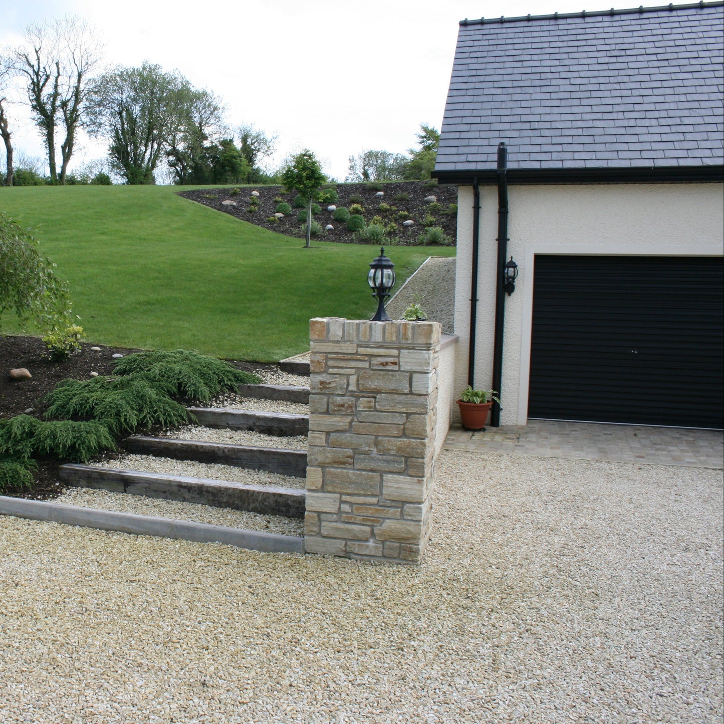 Garden with stone steps leading up to a garden pathway. Chipping used is 14mm Gold Donegal Quartzite Stone Chipping.