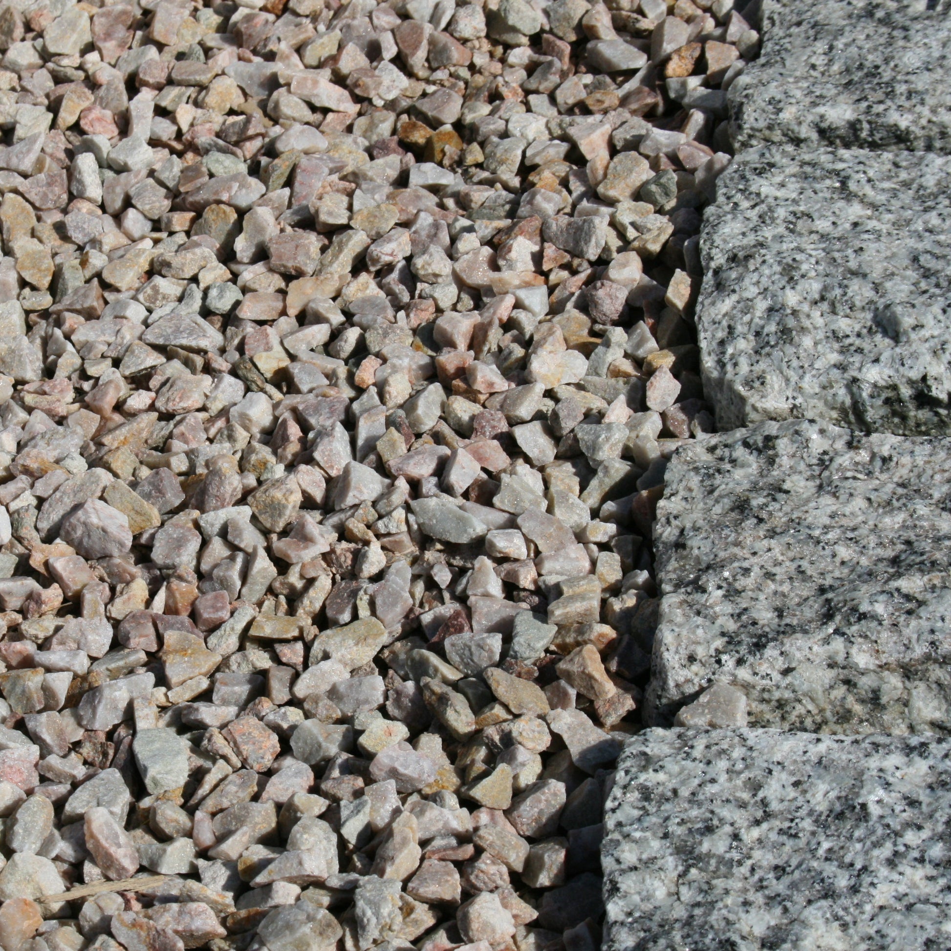 Close up of 
14mm Rose Gold Quartzite Stone Chipping beside Silver Granite Cobbles. 