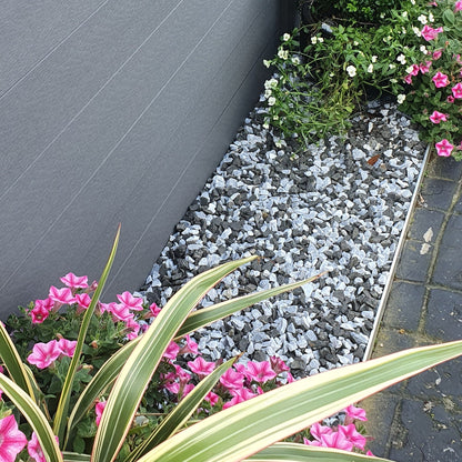 Garden with flowers and plants against a grey fence