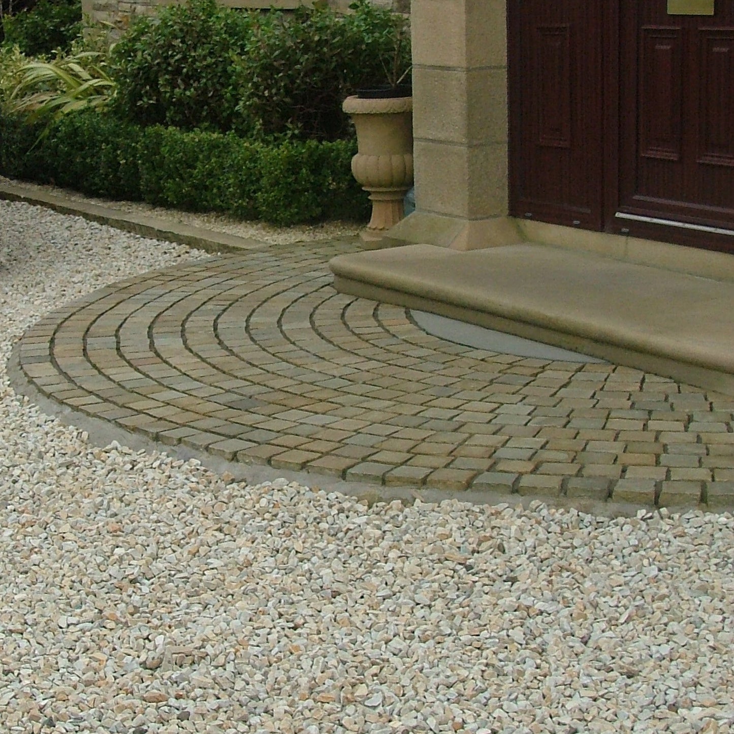 Driveway with a curved stone path leading to a house entrance. Driveway features 20mm Gold Donegal Quartzite Stone Chipping.