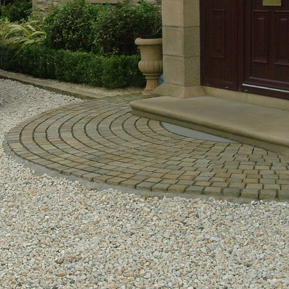 Driveway with a curved stone path leading to a house entrance. Driveway features 20mm Gold Donegal Quartzite Stone Chipping.