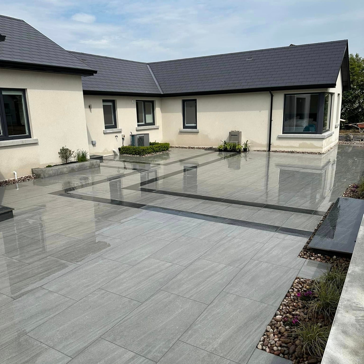 An outdoor installation of Ashen porcelain paving tiles in a garden setting, with a ash grey colour.