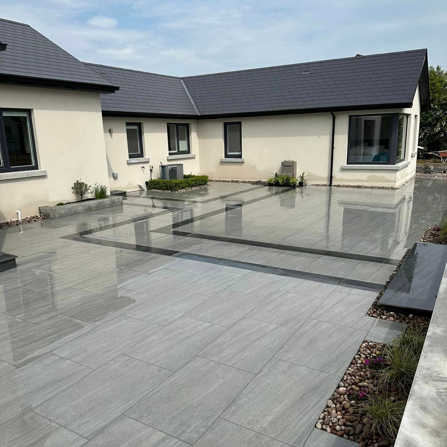 An outdoor installation of Ashen porcelain paving tiles in a garden setting, with a ash grey colour.