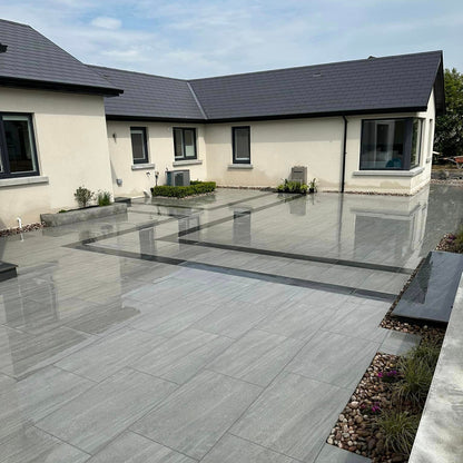 An outdoor installation of Ashen porcelain paving tiles in a garden setting, with a ash grey colour.