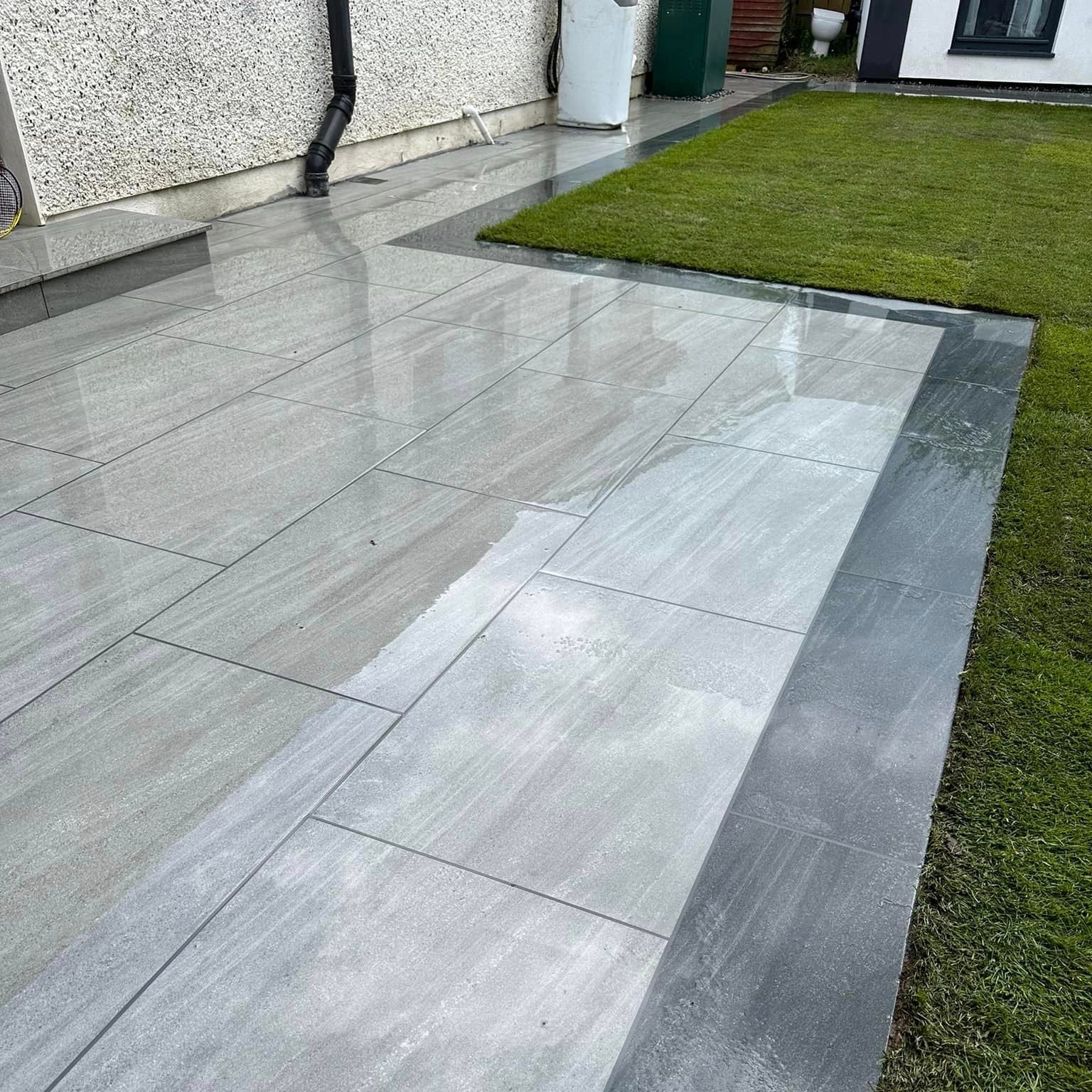 Small patio and pathway installation of Ashen porcelain paving tiles in a garden setting.