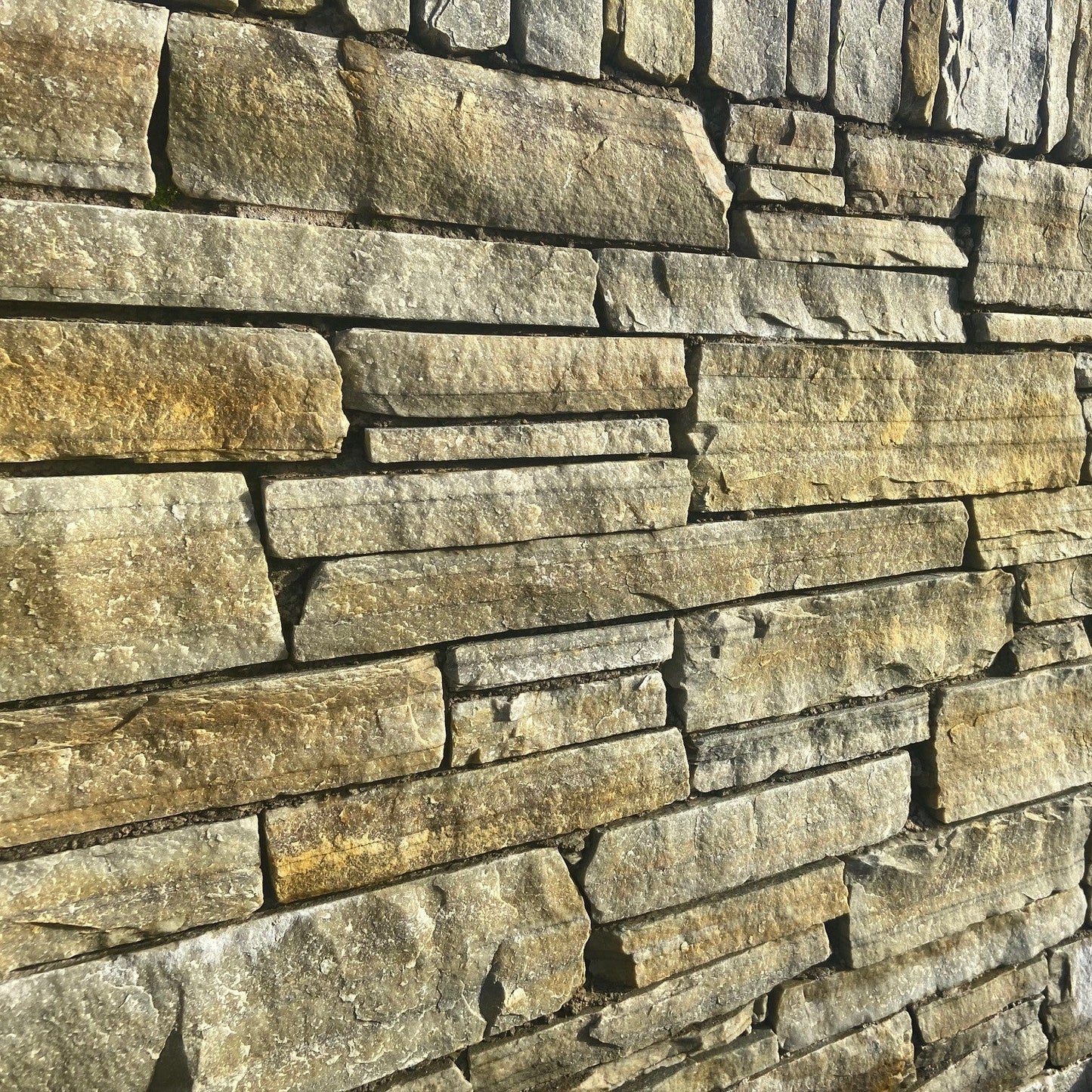 Close-up of a stone wall with varying shades of grey and brown. This stone is called Atlantic Grey Donegal Quartzite Machined.