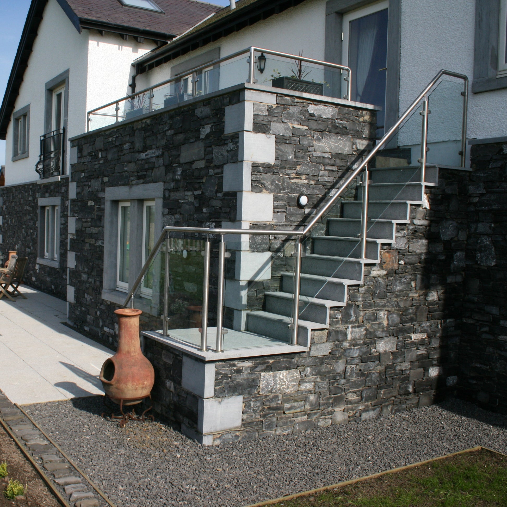 Modern house exterior with bespoke blue limestone staircase and garden area. 