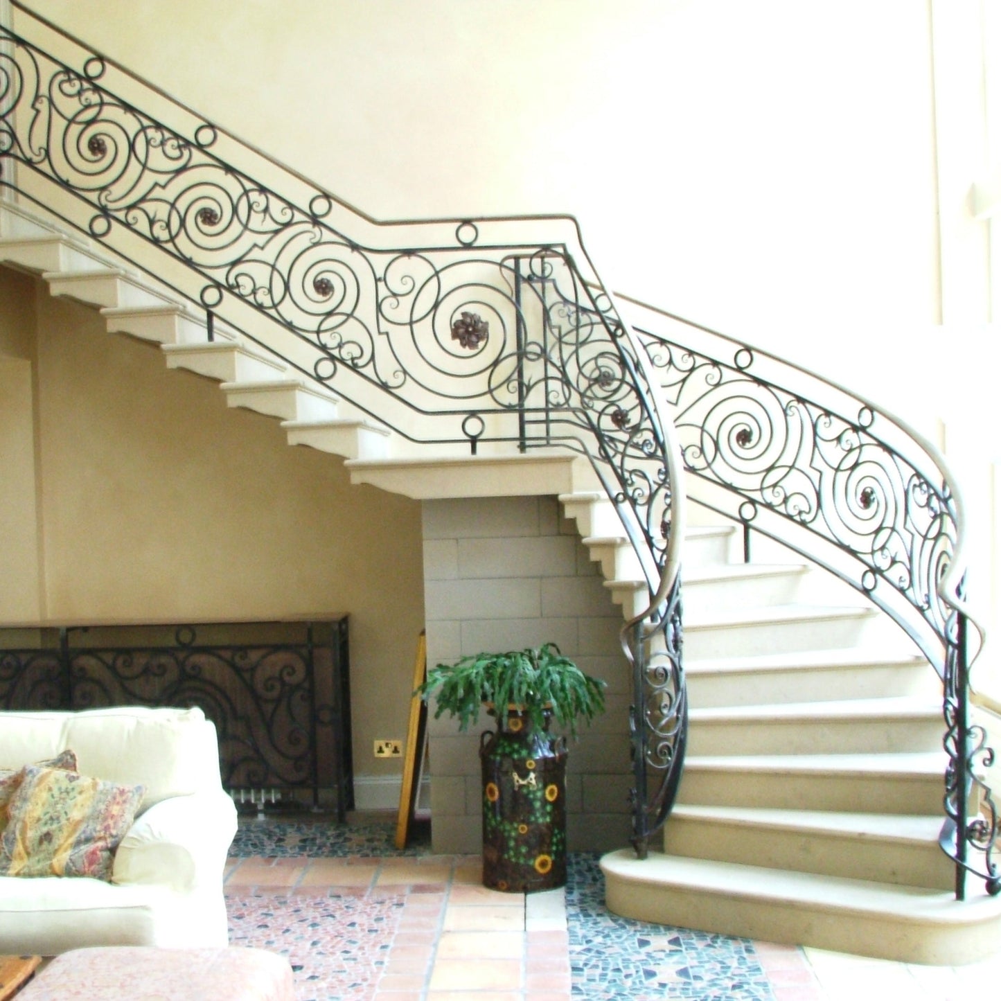 Decorative sandstone staircase with ornate railings in a home interior.