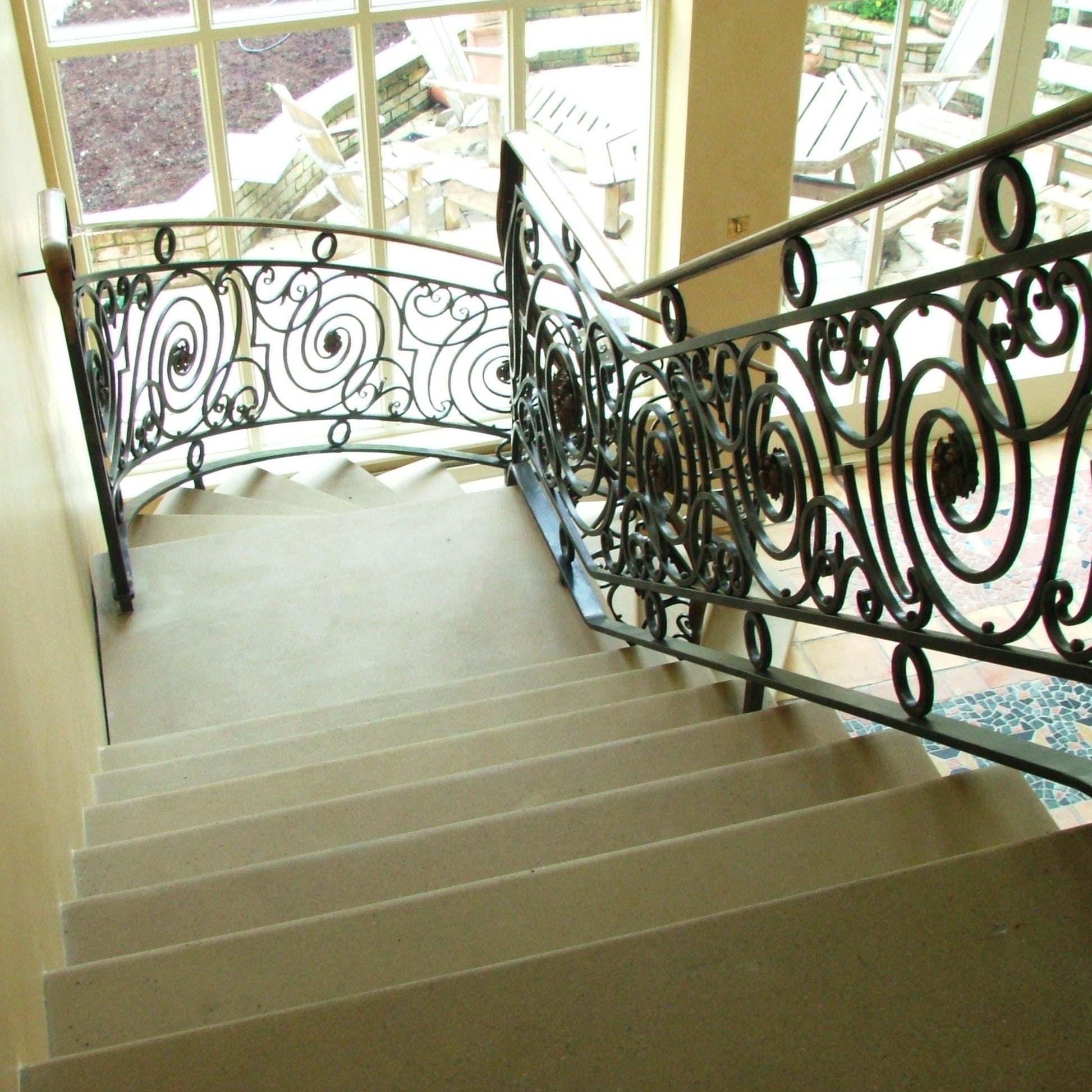 Architectural Sandstone Staircase with decorative wrought iron railing in a well-lit room.