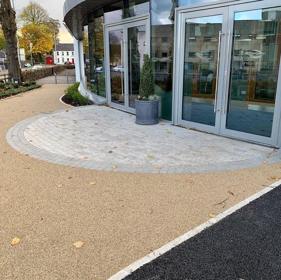 Entrance to a building with a circular paving design featuring Black Granite Cobble border and potted plants.
