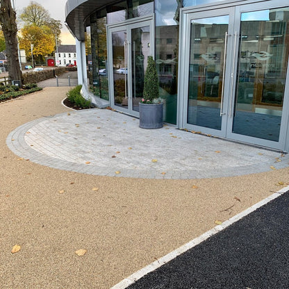 Entrance to a building with a circular paving design featuring Black Granite Cobble border and potted plants.