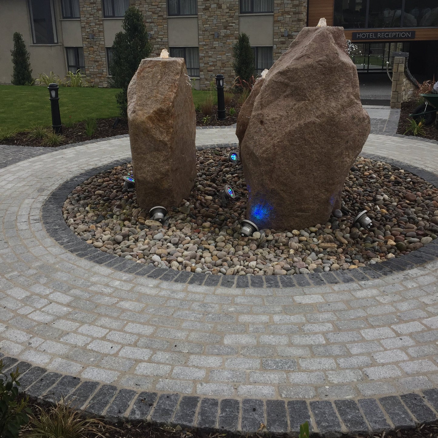 Stone monoliths in a circular stone pathway completed using Silver & Black Granite Cobbles in 200 x 100mm with a building in the background.
