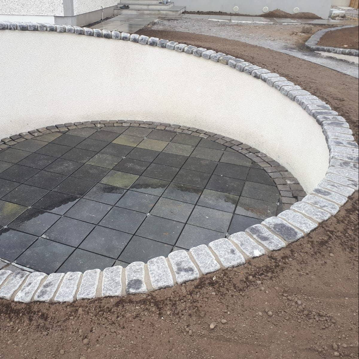 Circular pathway with a sunken patio area. Pathway wall completed using Black Granite Cobbles. 