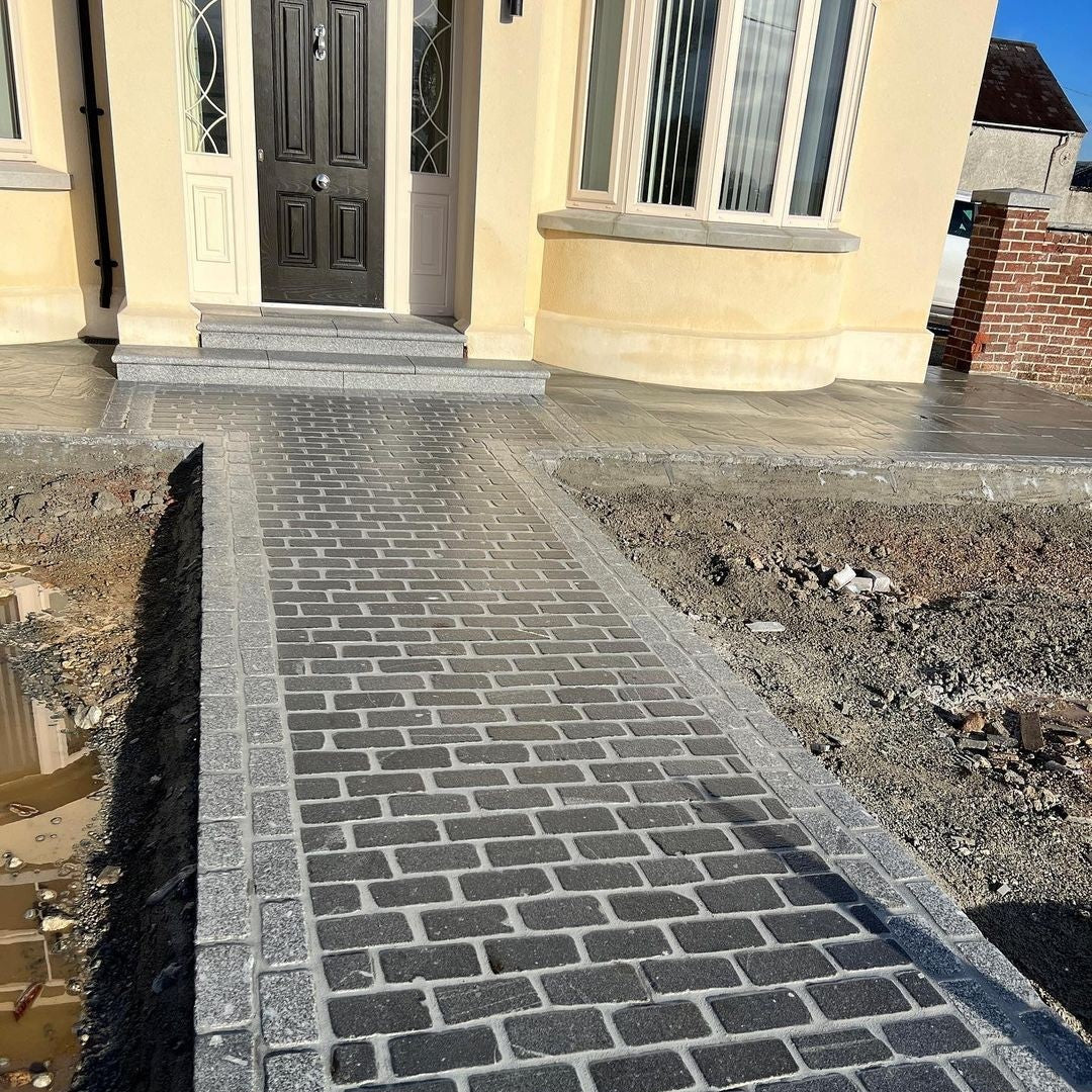 Newly laid stone pathway using Black Granite & Silver Granite Cobbles in 200 x 100mm size leading to a house entrance. 