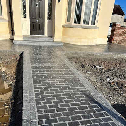 Newly laid stone pathway using Black Granite & Silver Granite Cobbles in 200 x 100mm size leading to a house entrance. 