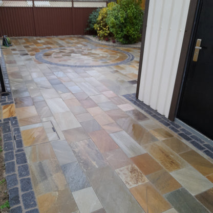 Outdoor patio in Donegal Quartzite Paving and Black Granite Cobbles laid as a unique contrasting border and circle design. 