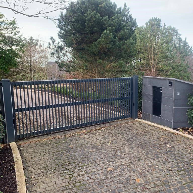 Automated gate with a security shed in a driveway surrounded by trees. Laneway features Black Granite Cobbles in 100 x 100mm size. 