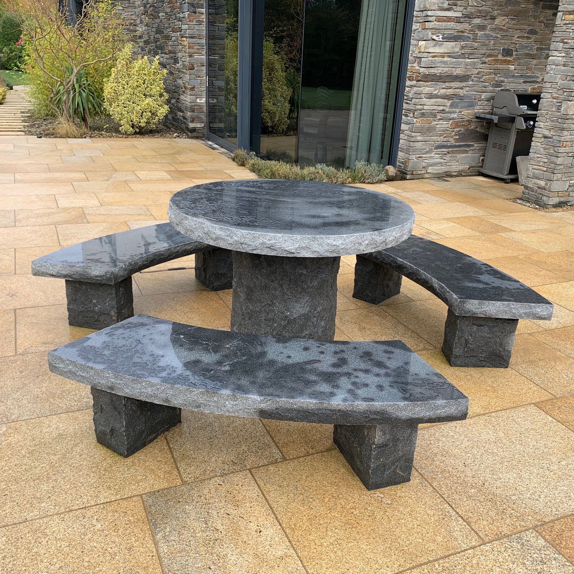 Black Granite picnic table and benches on a gold granite patio with a stone building in the background
