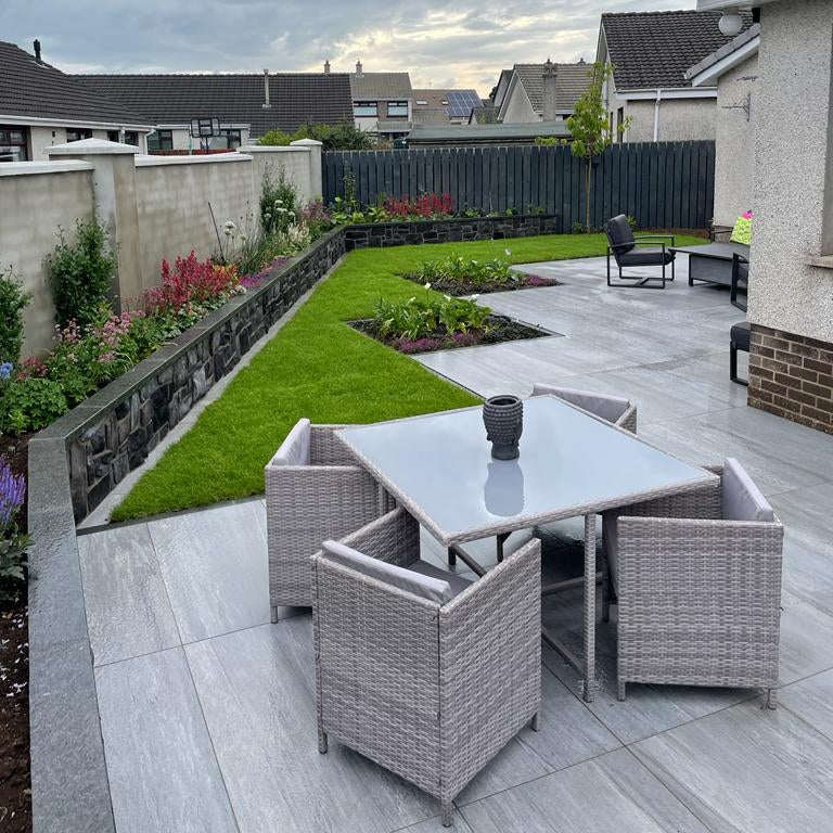 Outdoor patio area with a table and chairs in a residential backyard. Planter wall completed using Black Granite Wall Capping.