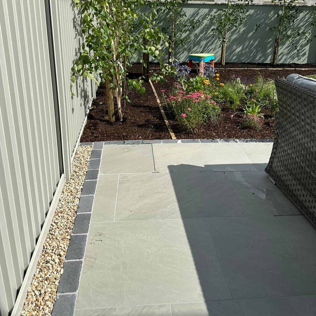 Porcelain patio bordered with Black Limestone Paving Cobbles 200 x 100mm 