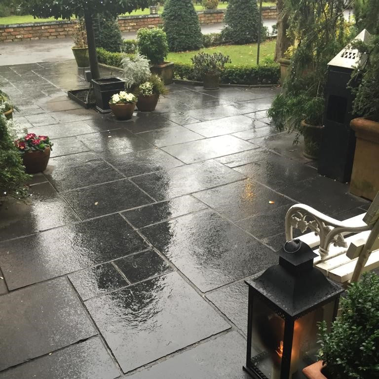 patio area with potted plants and lantern. Paving is Black Limestone. 