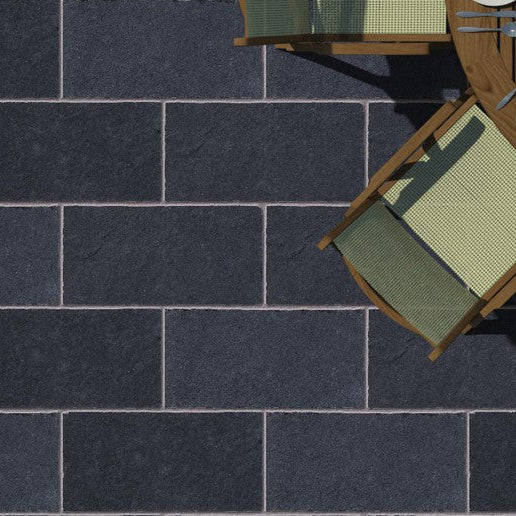 Top-down view of a patio with Black Limestone Paving slabs in 600 x 300mm size with wooden tables, and green chairs.