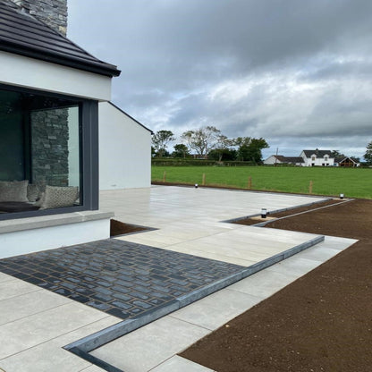 Large modern porcelain patio featuring Black Limestone Paving Cobbles in 200 x 100mm size. 
