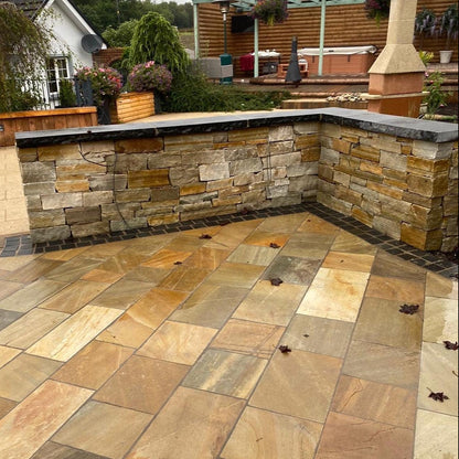 Outdoor patio with stone pavement and a stone wall in Donegal Quartzite. Border cobble in Black Limestone in 100 x 100mm size. 