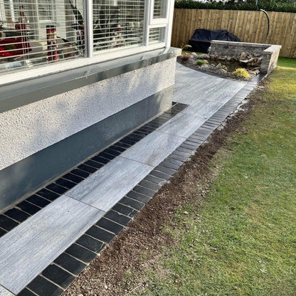 Porcelain pathway with a row of Black Limestone Paving Cobbles on either side. 