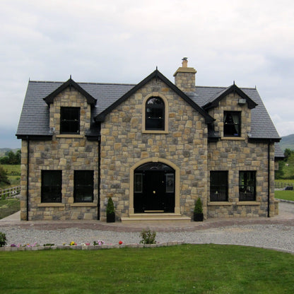 Stone house with a driveway and green landscape. Stone is Blue Centre Sandstone Machined and Architectural Sandstone Surrounds, Sills and Steps. 
