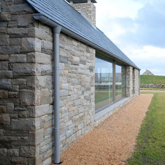Stone building with large windows and a grassy area in the background. Stone is Blue Grey Sandstone Machined. 