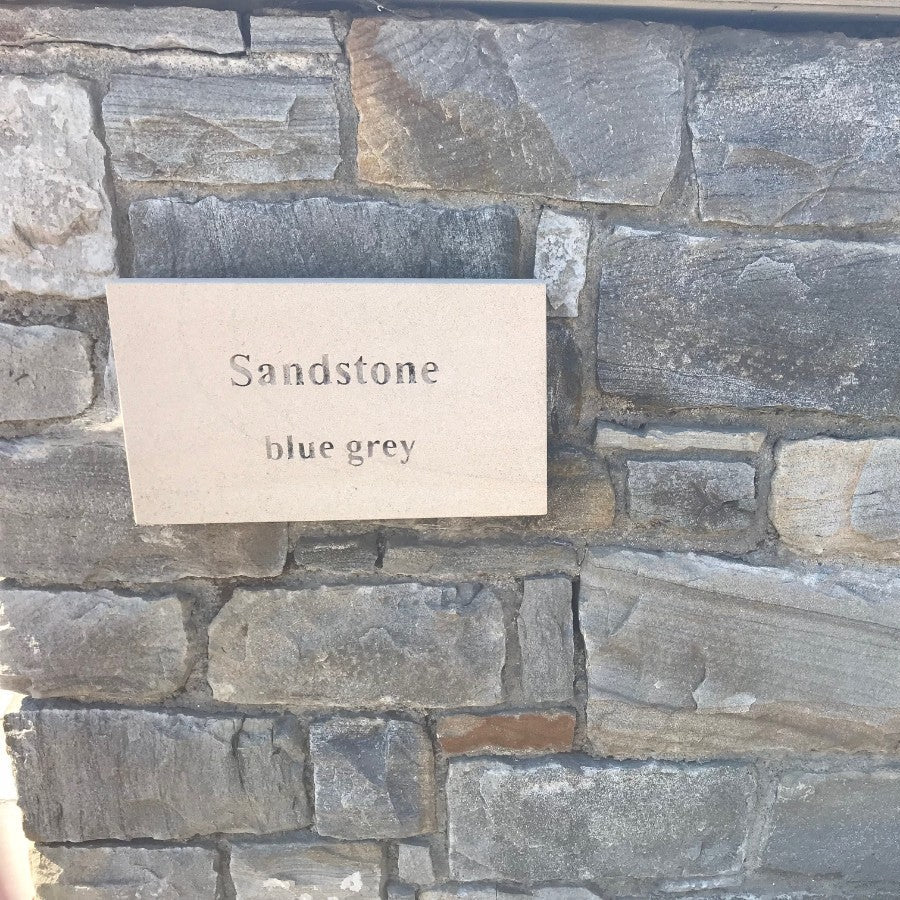 Close up of Blue Grey Sandstone Machined walling stone with a sandstone plaque. 