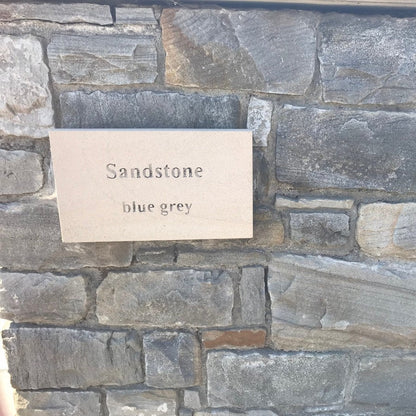 Close up of Blue Grey Sandstone Machined walling stone with a sandstone plaque. 