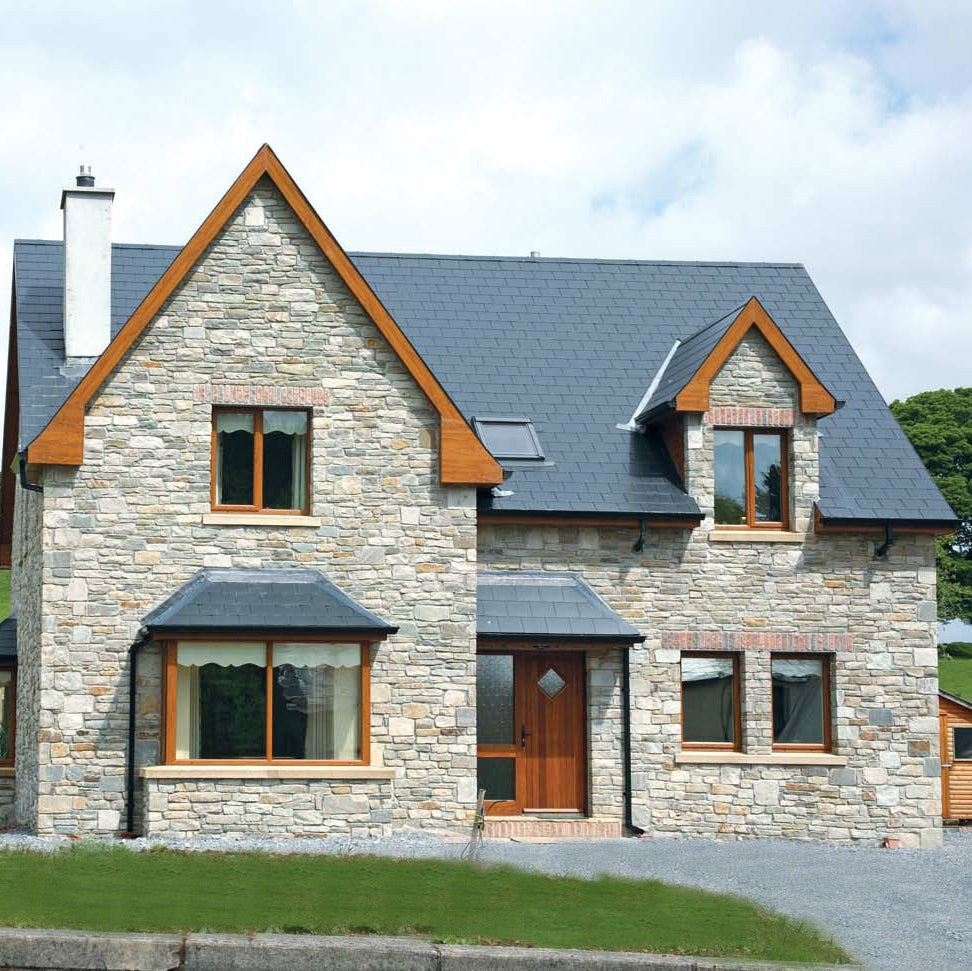 Stone house with wooden accents on a grassy hillside. Stone is Blue Grey Sandstone Machined. 