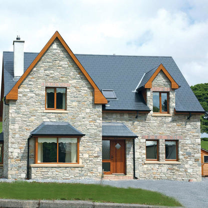 Stone house with wooden accents on a grassy hillside. Stone is Blue Grey Sandstone Machined. 