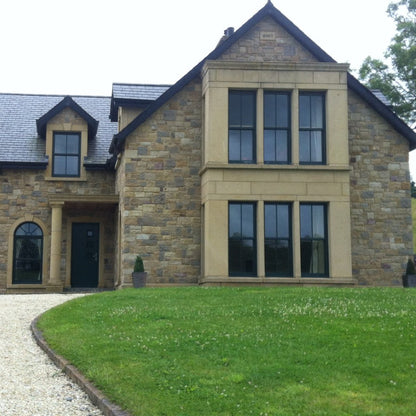 Large stone house with architectural sandstone surrounds and column. Stonework is Blue Grey Sandstone Machined.