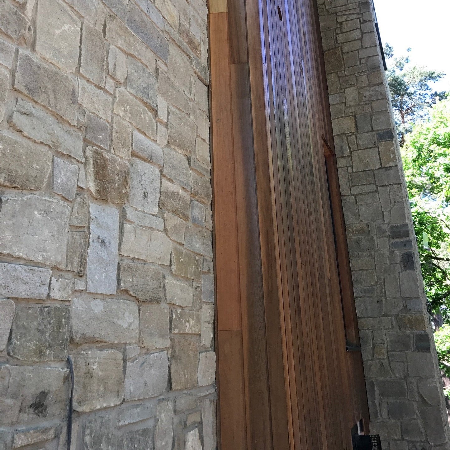 Close up of a stone-clad building featuring a stonework mix containing Blue Grey Sandstone Stoneer Cladding. 