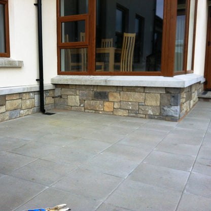 Low stone wall featuring a mix containing Blue Grey Sandstone Stoneer Cladding. 