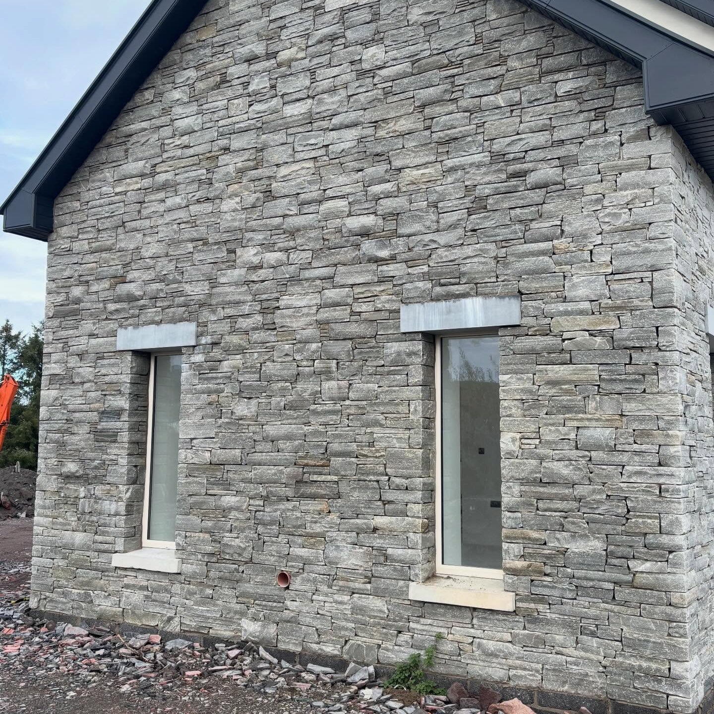 House with stone façade and two windows with bespoke blue limestone lintels on a clear day.