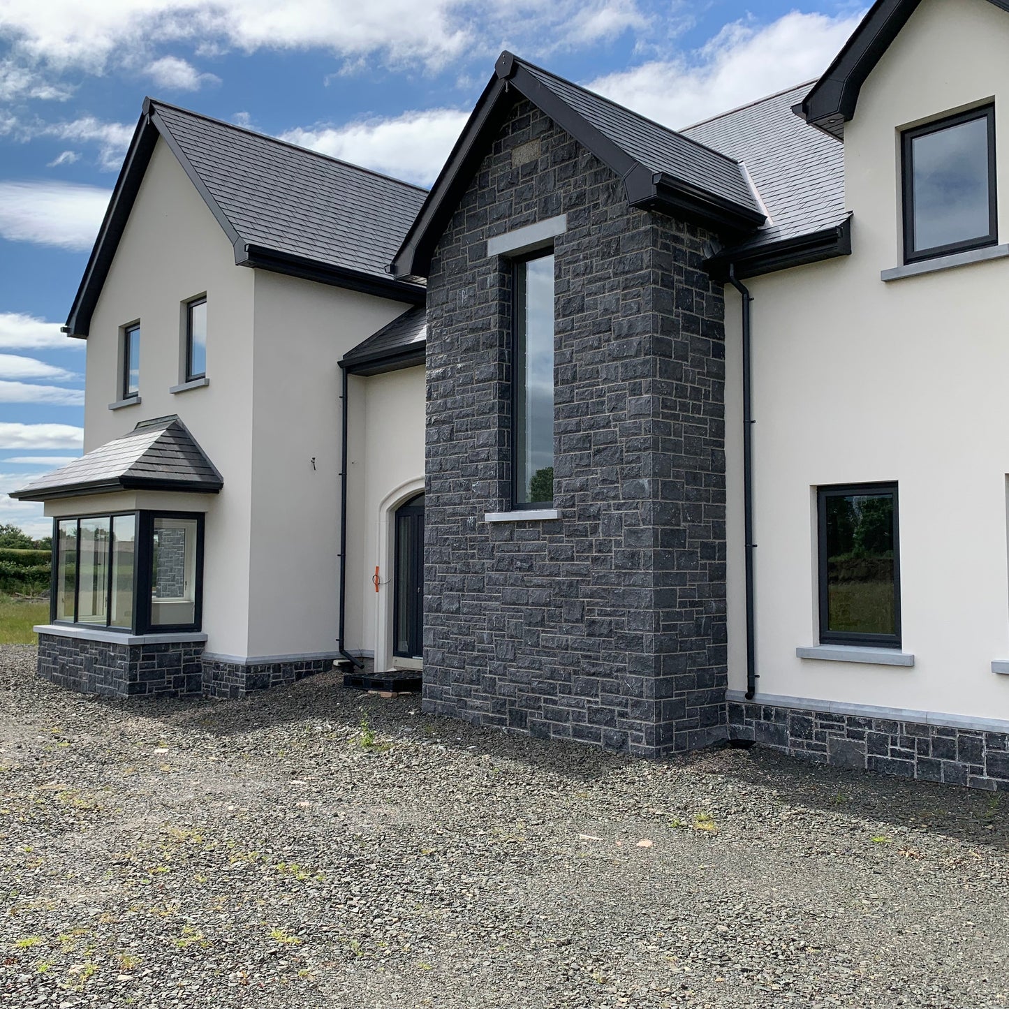 Modern house with blue limestone building stone and white exterior on a clear day.