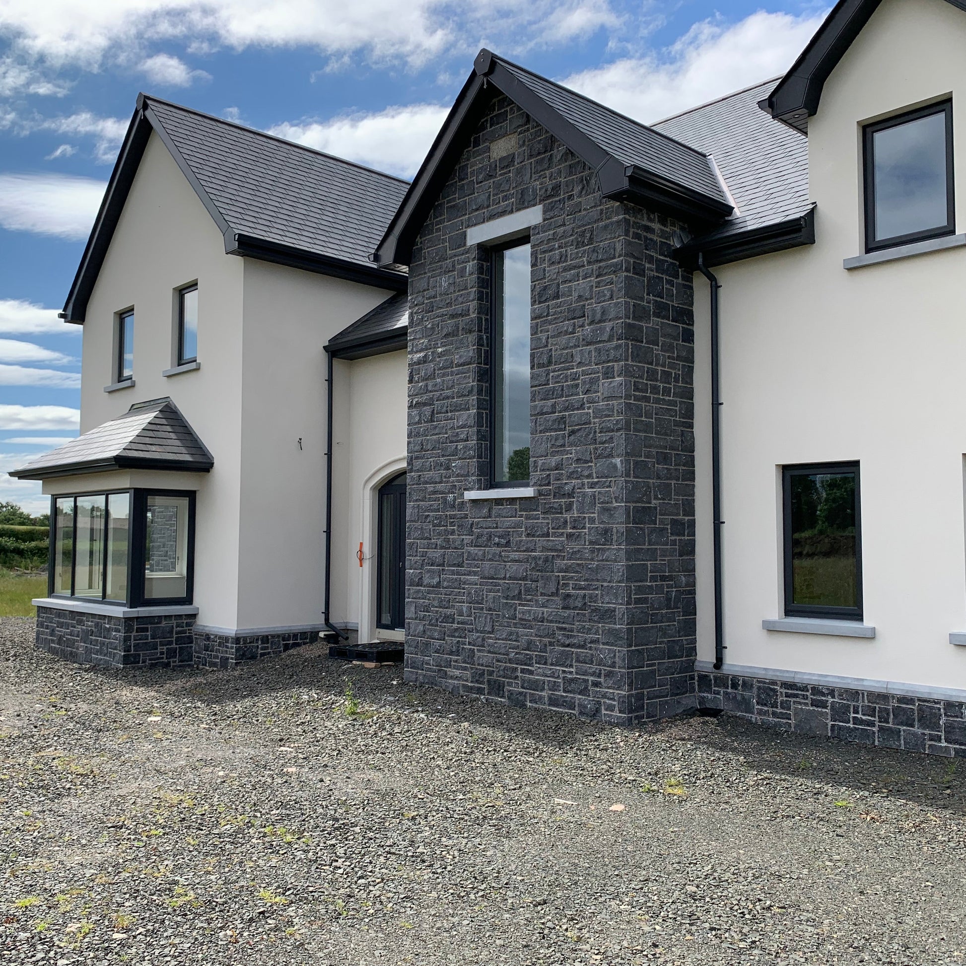 Modern house with blue limestone building stone and white exterior on a clear day.