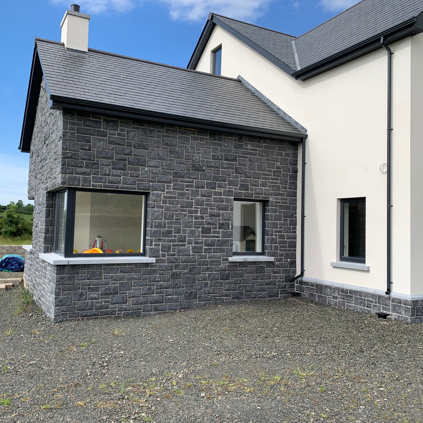 Modern house with blue limestone facade and white exterior walls under a blue sky.