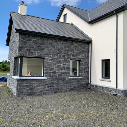 Modern house with blue limestone facade and white exterior walls under a blue sky.